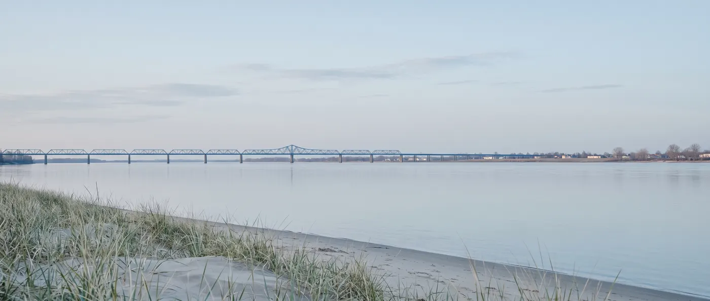 Large fleuve calme et long pont au petit matin